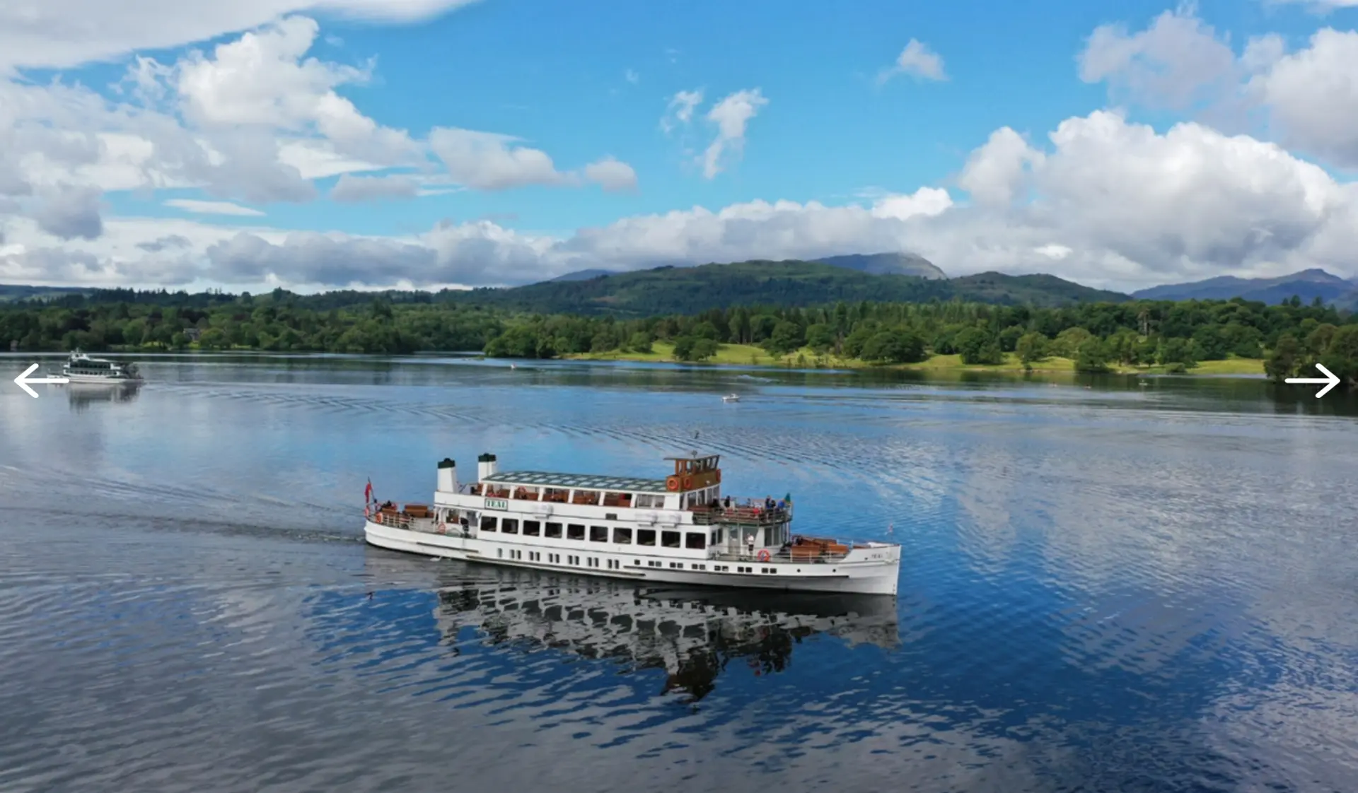 The MV Teal steamer cruising on Lake Windermere with fells and blue sky beyond